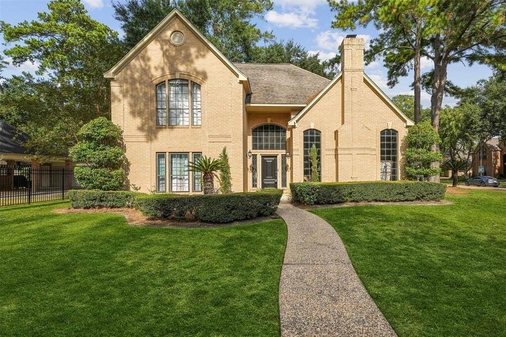 This elegant brick home features stunning curb appeal with manicured landscaping, tall windows, and a welcoming front entrance.