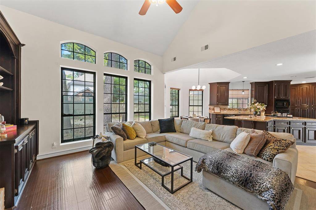 Stunning living room with vaulted ceilings, a cozy fireplace, and walls of windows overlooking the backyard.