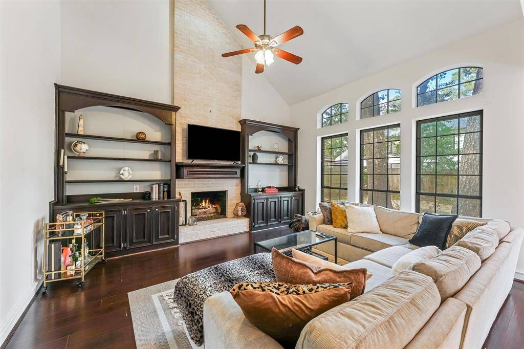 This inviting living room features a floor-to-ceiling brick fireplace, custom built-ins, and a wall of windows for incredible natural light.