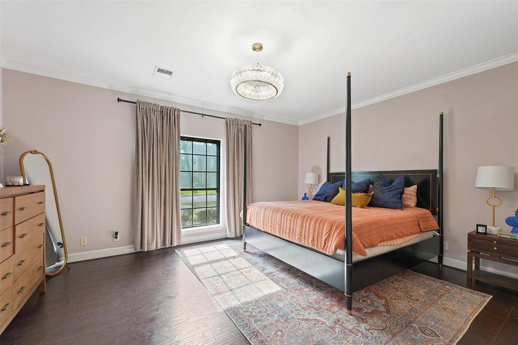 The spacious primary suite offers elegant comfort with natural light and a statement chandelier.
