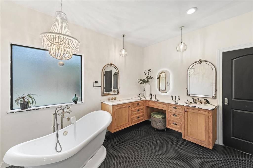 A luxurious primary bath showcases a freestanding soaking tub, elegant chandelier, and dual vanities with stylish marble countertops.
