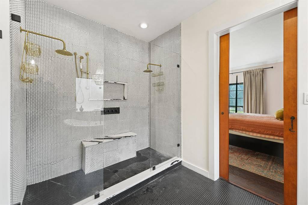 A stunning walk-in shower showcases designer tile, dual rain shower heads, and elegant brass fixtures for a spa-like experience.