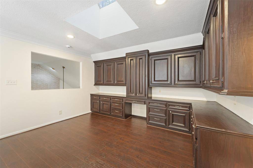 A spacious upstairs workspace with custom cabinetry and rich wood flooring offers the perfect spot to study or work from home.