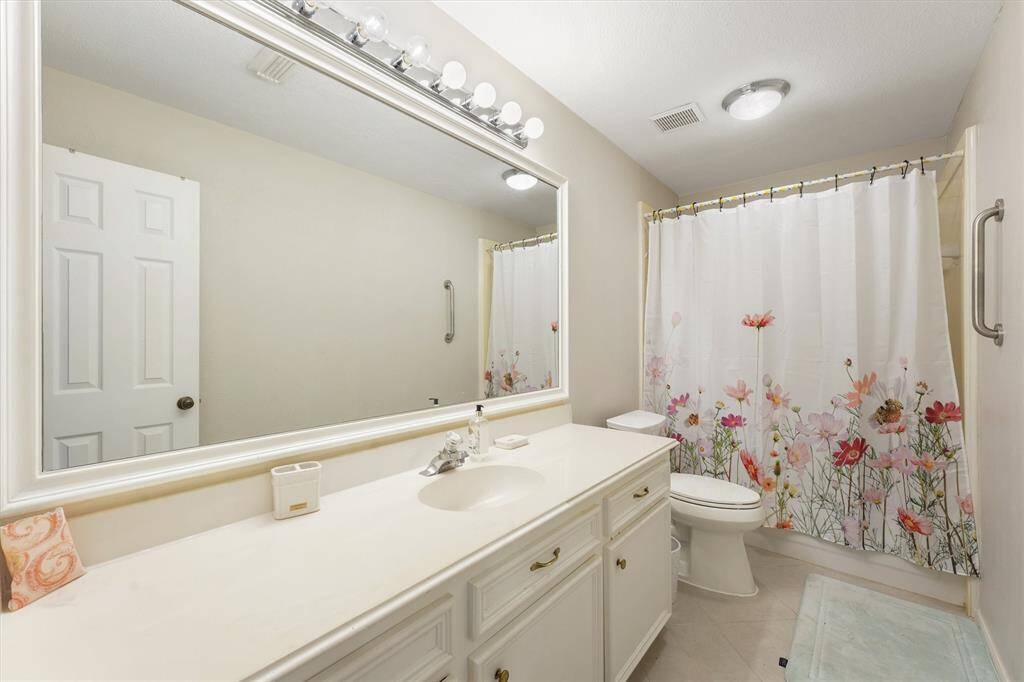 This full bathroom features a spacious vanity, bright lighting, and cheerful accents for a fresh, inviting feel.