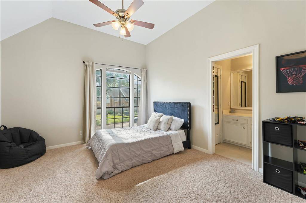 This bright bedroom features vaulted ceilings and a beautiful wall of windows overlooking the yard.