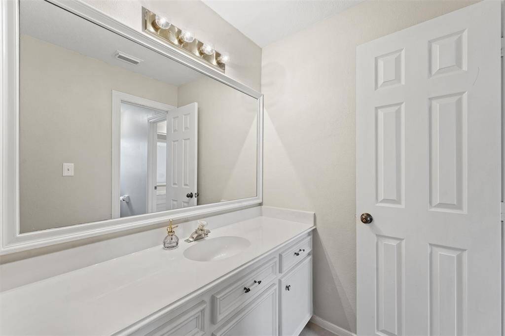 Clean and classic, this full bath boasts a long countertop, ample storage, and bright lighting.
