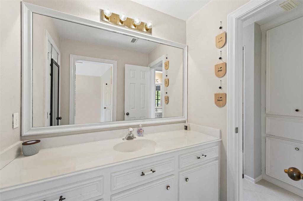 This additional full bathroom features a wide vanity and framed mirror, for a warm, personal touch.