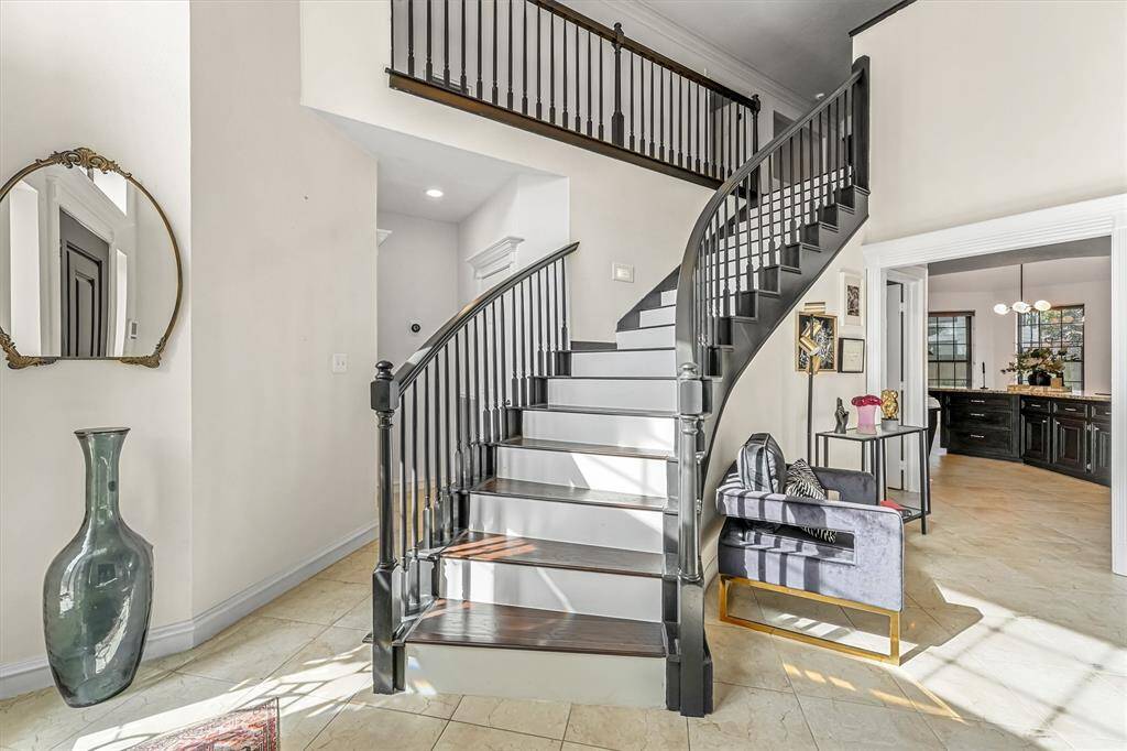 This elegant entryway features a dramatic curved staircase, soaring ceilings, and a seamless flow into the open-concept floor plan.