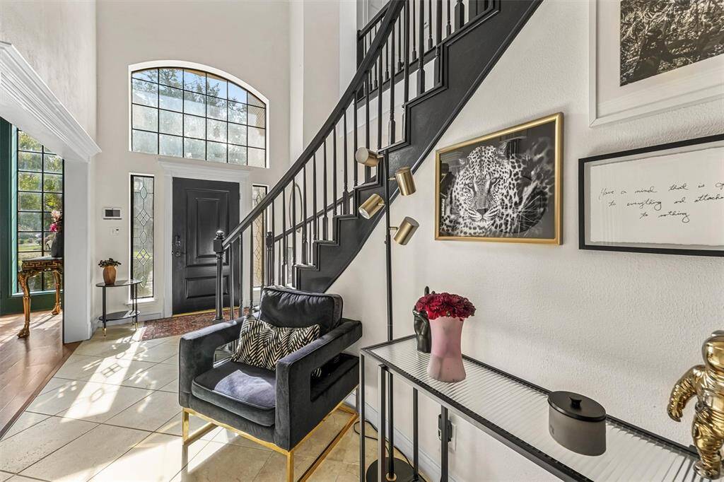 The grand entryway showcases high ceilings, abundant natural light, and a striking staircase that sets the tone for the stylish interior.