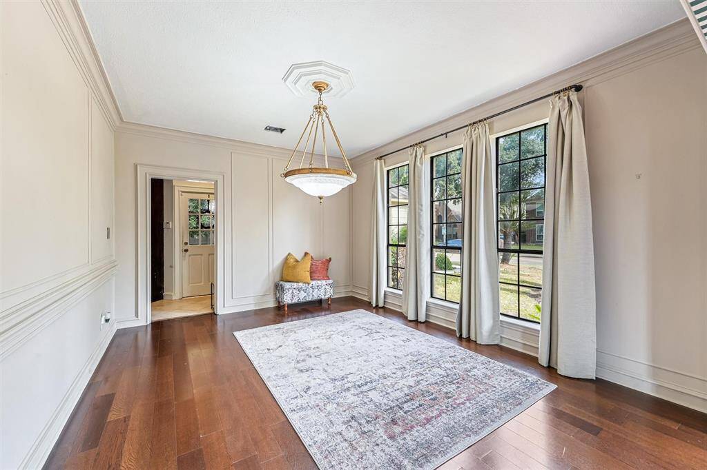 The elegant dining room features wood floors, wall molding, and large windows that flood the space with light.