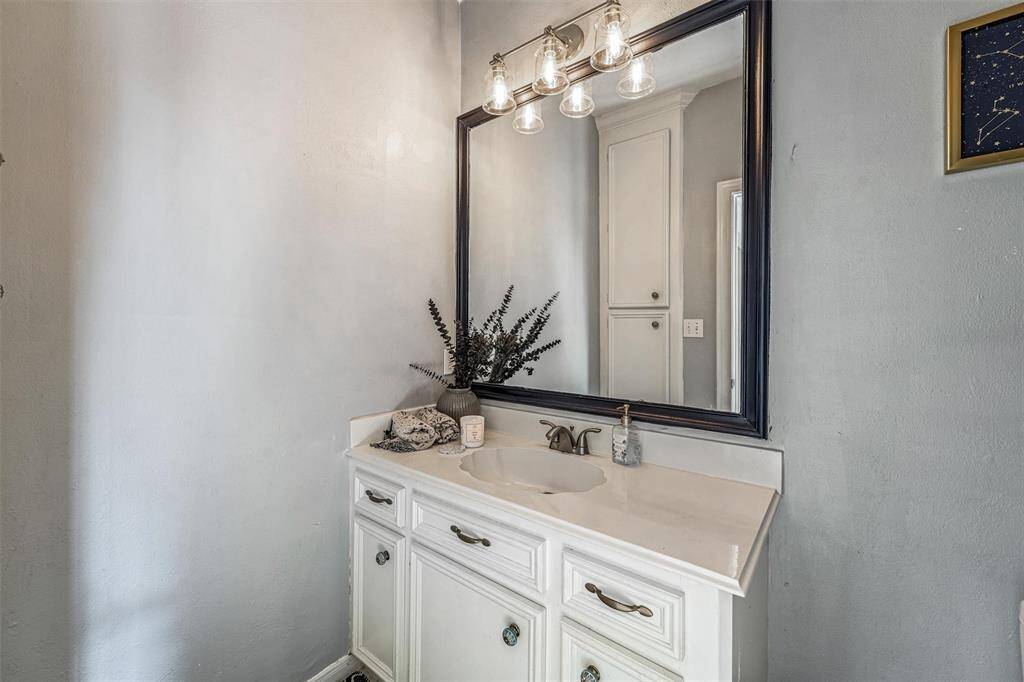 This charming powder room is complete with a framed mirror, updated lighting, and vintage-inspired vanity.