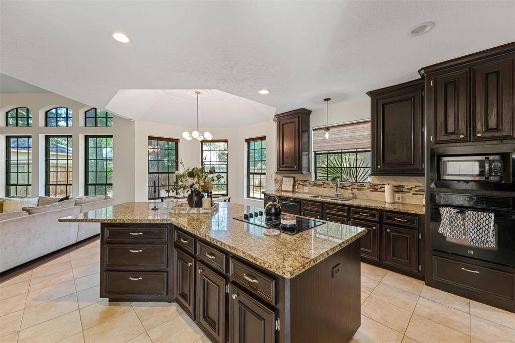 The kitchen boasts granite countertops, rich dark cabinetry, a center island cooktop, and generous prep and storage space.