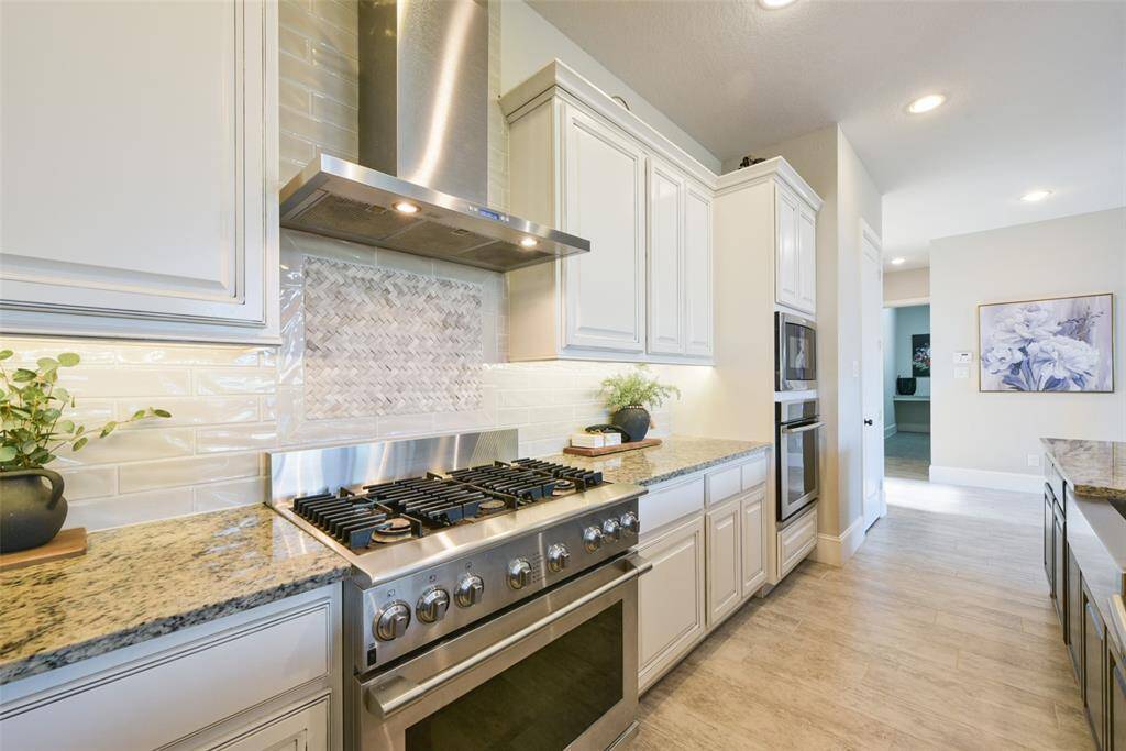 Beautiful tile backsplash and accent tile centered above the range. Kitchen boasts two ovens and 6 burner gas range.