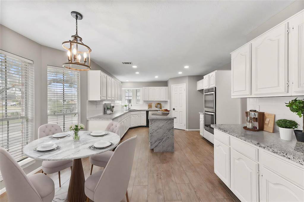 The kitchen makes way to a light, bright, and sunlilt breakfast room that offers a bay window with park-like views and a built-in buffet area for bonus storage and serving space, complete with more granite countertops & a subway tile backsplash.