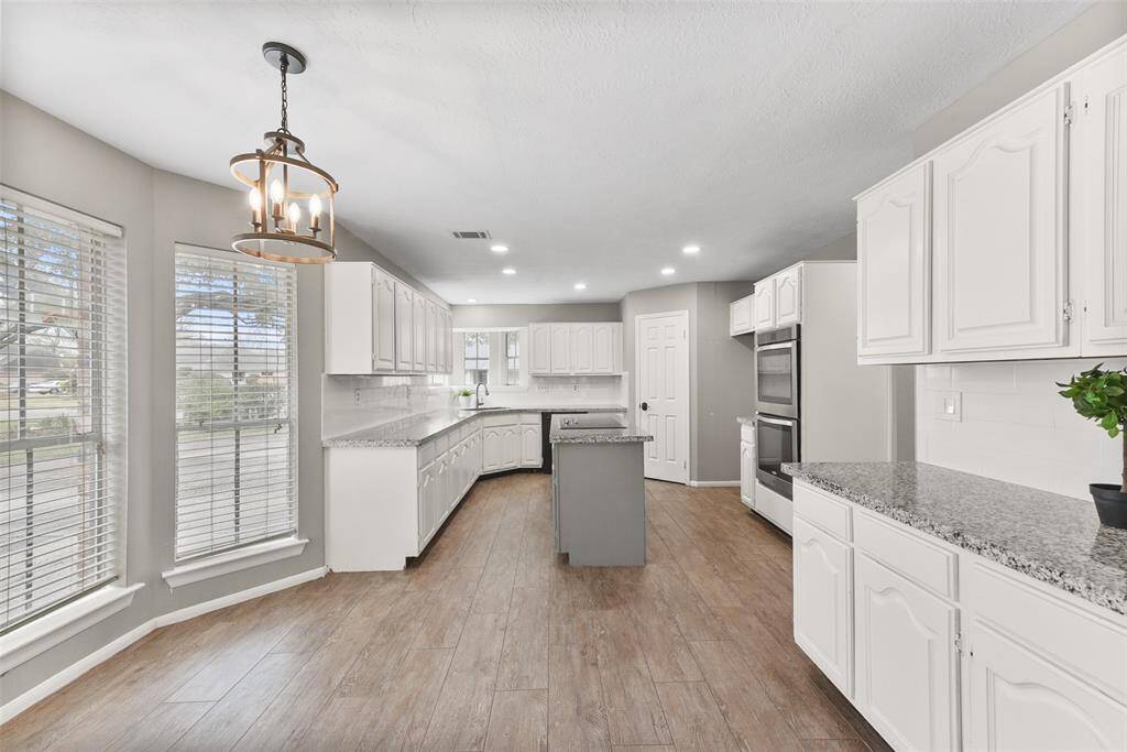 The kitchen makes way to a light, bright, and sunlilt breakfast room that offers a bay window with park-like views and a built-in buffet area for bonus storage and serving space, complete with more granite countertops & a subway tile backsplash.