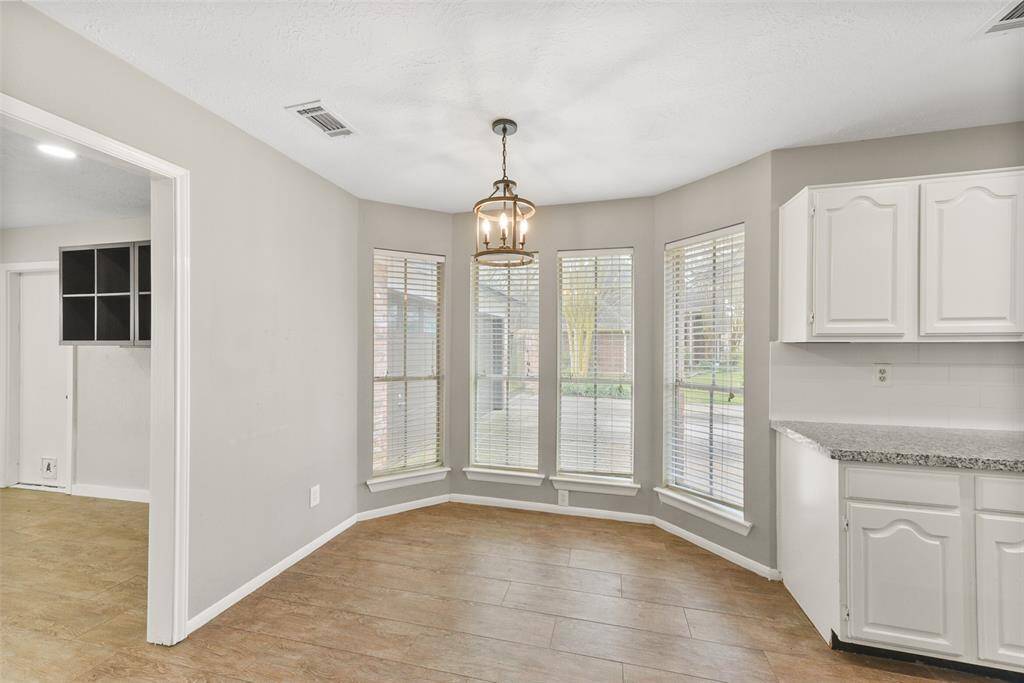 The kitchen makes way to a light, bright, and sunlilt breakfast room that offers a bay window with park-like views and a built-in buffet area for bonus storage and serving space, complete with more granite countertops & a subway tile backsplash.