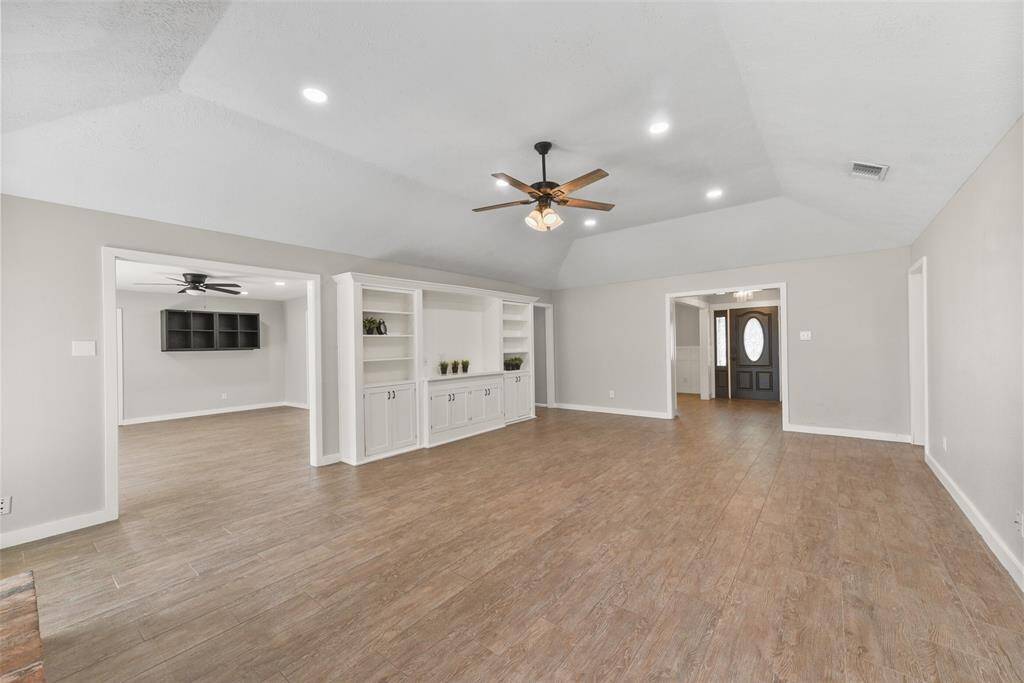From the foyer or the flex-use gameroom, you can access this comfortable and inviting family room with an elevated gambrel ceiling, a lighted ceiling fan, recessed lights, wood-look tile floors, and a custom-built entertainment hutch.