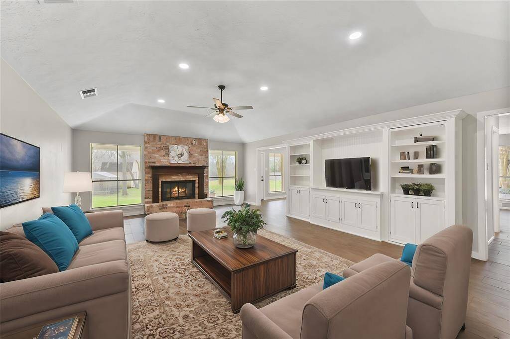 The family room is anchored by a charming wood-burning fireplace with a gas ignitor, a brick hearth, and a traditional wood mantle. The fireplace is flanked by a pair of rear-facing windows with picture-perfect views of the park-like backyard.