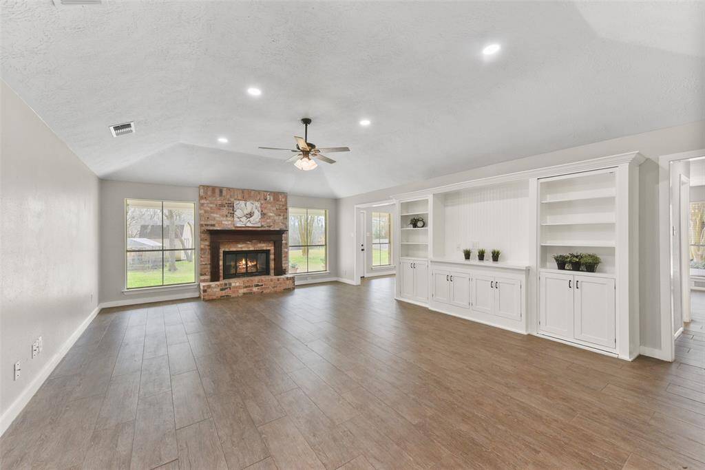 The family room is anchored by a charming wood-burning fireplace with a gas ignitor, a brick hearth, and a traditional wood mantle. The fireplace is flanked by a pair of rear-facing windows with picture-perfect views of the park-like backyard.