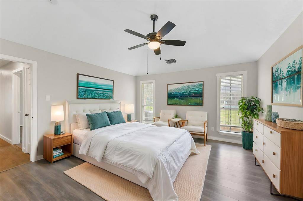 At the far end of the hallway, escape to this peaceful owners retreat complete with a modern lighted ceiling fan, numerous cased windows dressed with 2-inch blinds, wood-look tile floors, neutral paint, and a pocket door to the en suite bathroom.