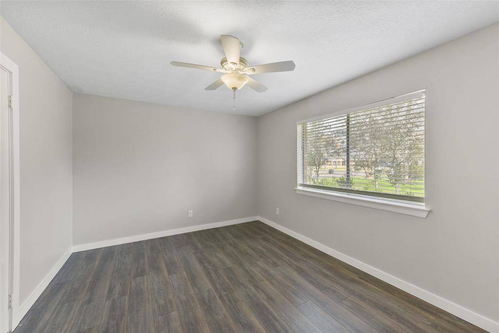 Another secondary bedroom is the largest of the three, measuring 15'x11' and also offering a lighted ceiling fan, fresh neutral paint, wood-look tile floors, a walk-in closet, and a side-facing window with views of four mature magnolia trees.