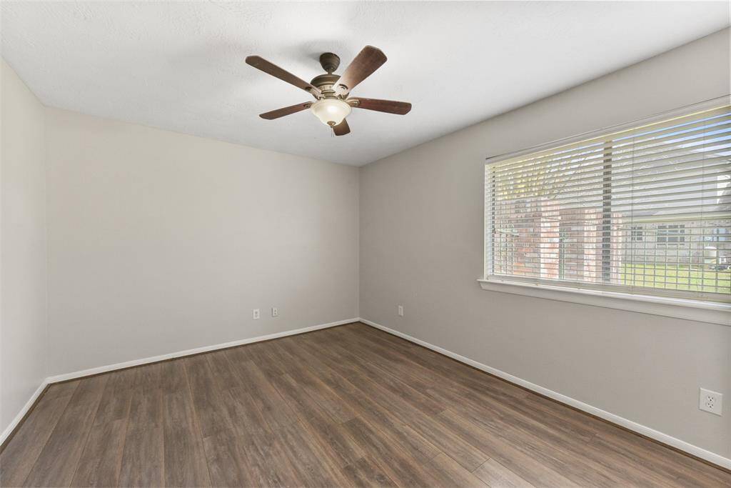 The fourth and final bedroom has all of the same finishes as the previous rooms, including fresh neutral paint, a lighted ceiling fan, wood-look tile floors, a generous closet, and an expansive window overlooking the side courtyard.