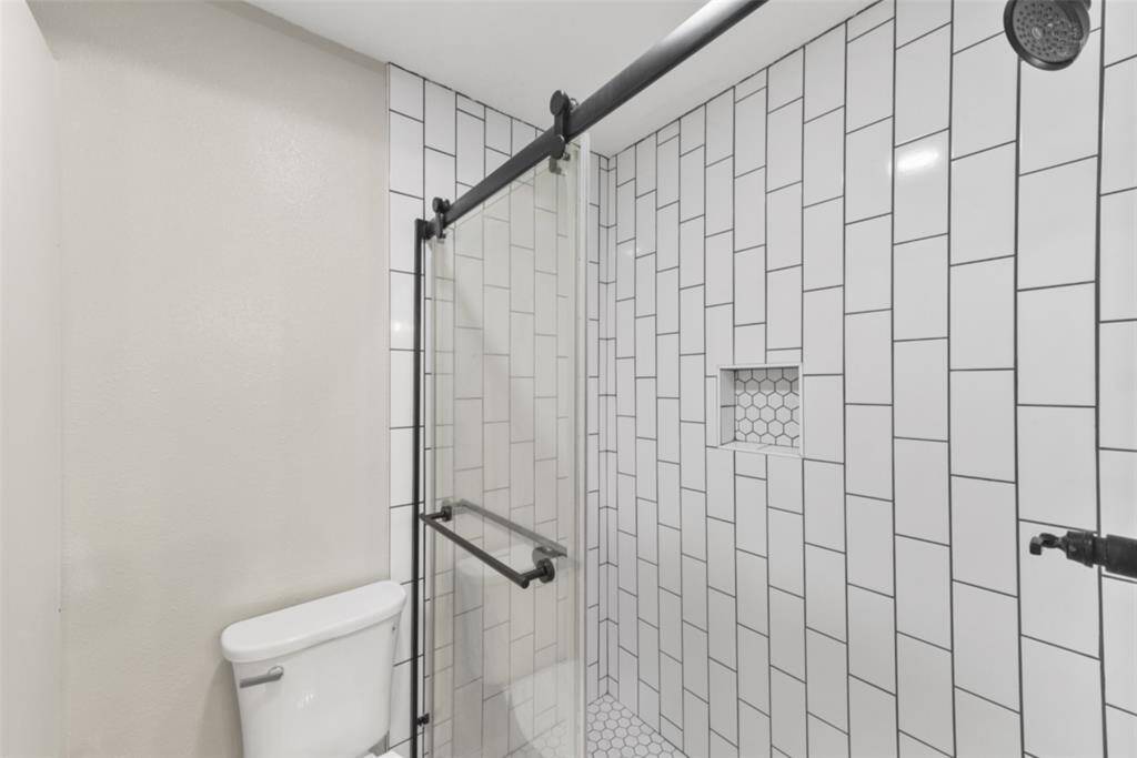 The guest bathroom has also been completely renovated to include a lengthy white vanity with stylish matte black hardware, a quartz countertop, dual rectangular sinks, framed mirrors, designer lighting, and an oversized shower with detailed tilework & a sliding glass door.