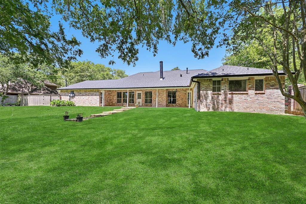 A half-panel glass door leads from the flex-use bonus room onto the lengthy covered back patio overlooking the huge 1.17-acre yard that includes a storage shed, a separate fenced pet area, and Spanish moss-draped trees sloping down to the creek bank.