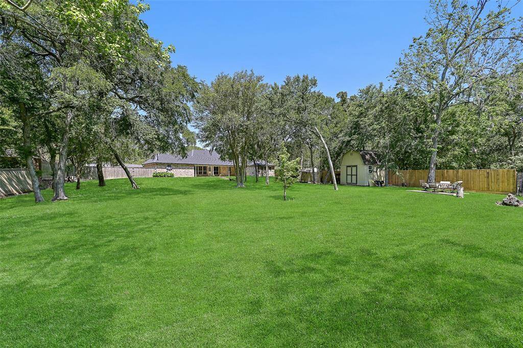 A half-panel glass door leads from the flex-use bonus room onto the lengthy covered back patio overlooking the huge 1.17-acre yard that includes a storage shed, a separate fenced pet area, and Spanish moss-draped trees sloping down to the creek bank.