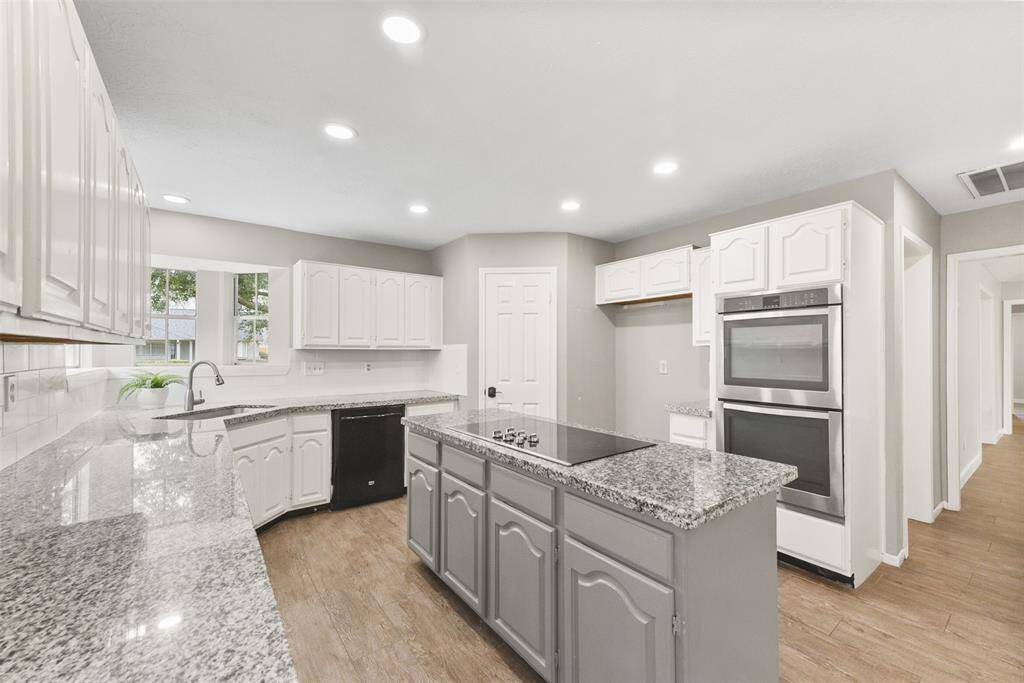 Step into this impressively updated island kitchen that features gleaming granite countertops atop crisp white cabinetry accentuated by a classic white subway tile backsplash. Also note the recessed lighting and contrasting paint color on the island.
