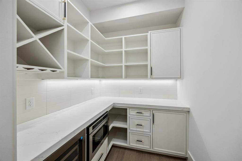 The butler pantry features quartz countertops, a coffee bar, wine cooler, built-in microwave/warmer drawer and under cabinet LED lighting.
