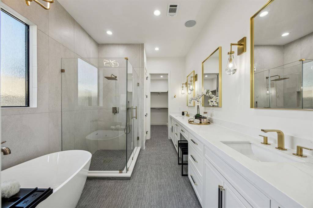 The primary bath features double sinks, a vanity, walk-in shower with frameless glass, and a free standing soaking tub.