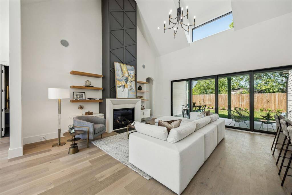 Elegant living room with high ceilings, featuring a custom gas log fireplace and beautiful white oak floors.