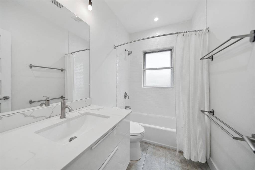 Floating vanity with storage, modern lighting and a tub/shower combo complete the secondary bath.