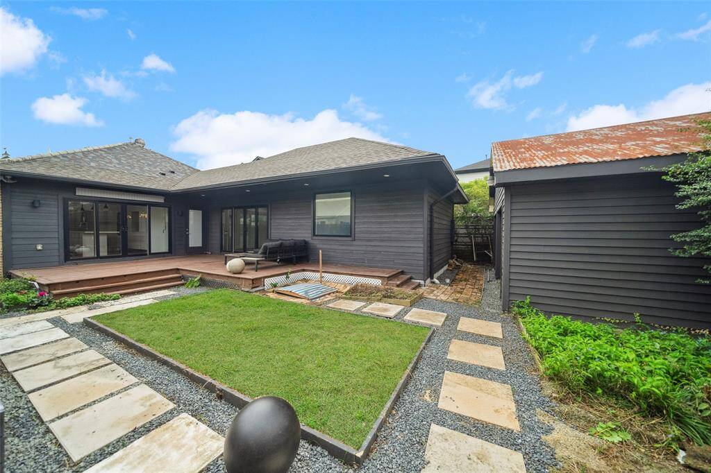 Beautifully designed deck and back yard. To the right, the former garage provides huge storage space, gym or studio.