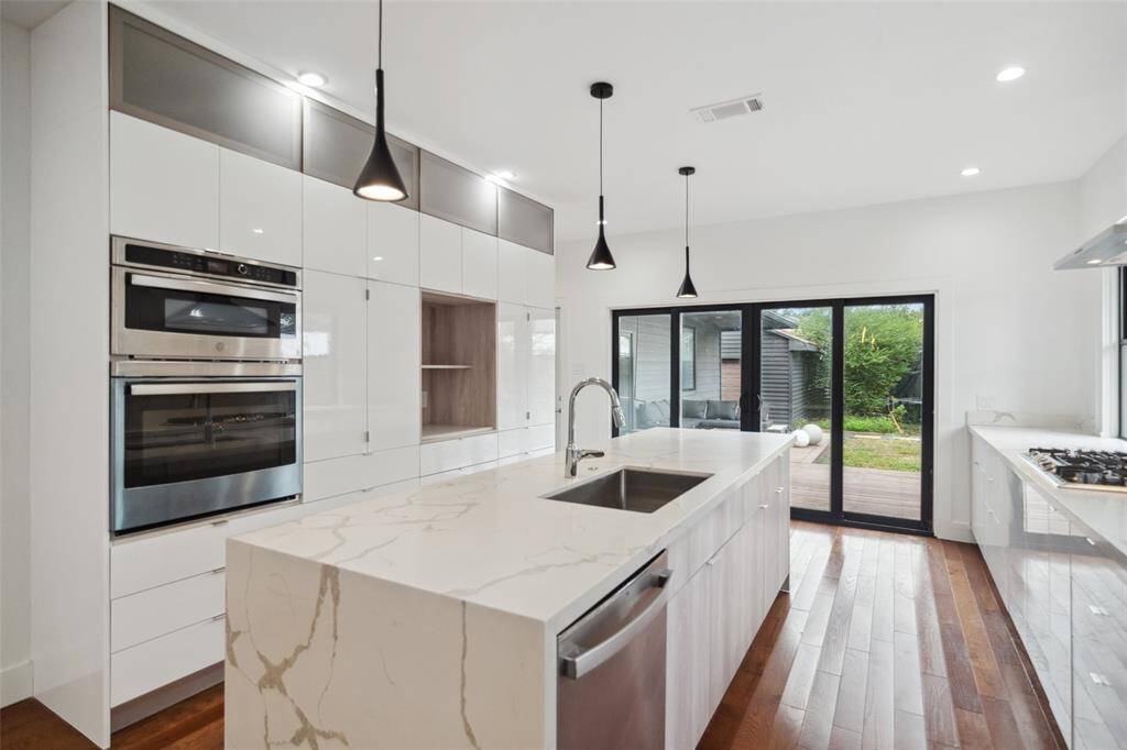 High gloss cabinetry complements the waterfall island and pendant lights.