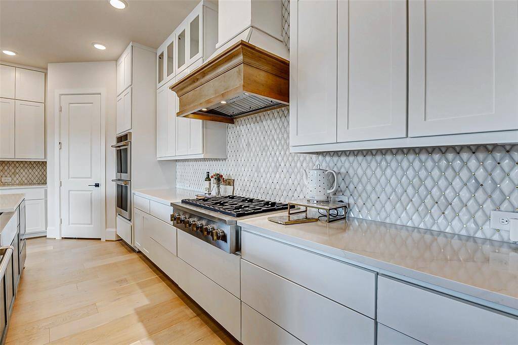 Additional features include a 36" 6-burner gas rangetop with a two-toned finish, complemented by a vent hood that seamlessly integrates with the cabinetry. The kitchen is further enhanced by GE 30" double electric convection ovens, adding both convenience and sophistication.