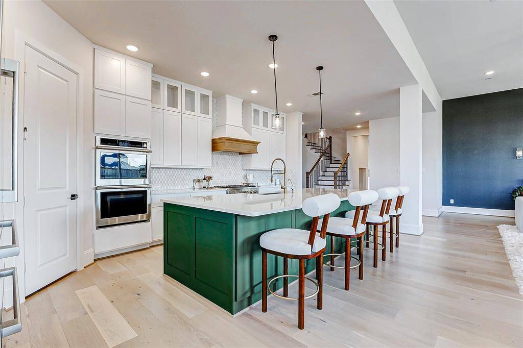 The expansive island offers generous seating, making it ideal for casual meals or a quick bite. Stunning quartz countertops are complemented by two elegant pendant lights, adding warmth and sophistication to the space. For added convenience, the microwave is seamlessly built into the island, and an under-sink RO filtration system ensures fresh, clean drinking water.
