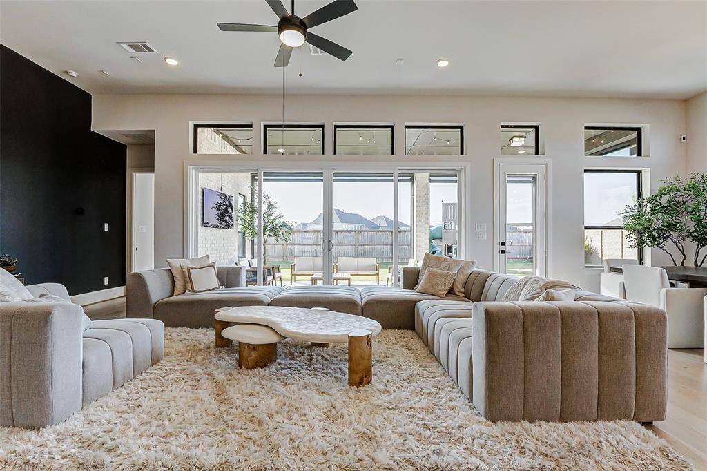 Let your gaze drift to the picture windows and wide glass sliding doors that line one wall, framing stunning views of the gorgeous backyard. With ample space for furniture, this living room is designed for both relaxation and entertainment.
