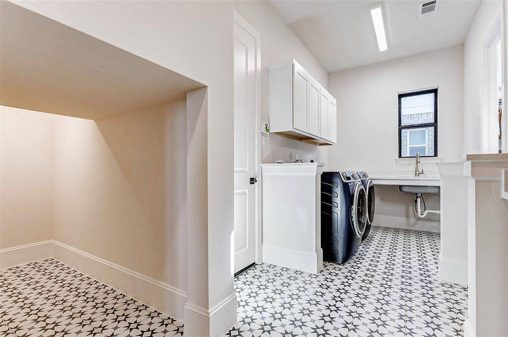 The expansive utility room is both stylish and functional, featuring eye-catching accent tile, built-in cabinetry for ample organization, and an additional storage area to keep everything neatly tucked away.