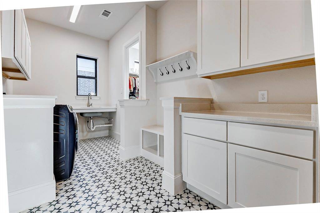 Conveniently accessible from both the garage and the primary suite, this thoughtfully designed space offers abundant counter space, ample cabinetry, and a utility sink. A built-in bench with a custom shelf above adds the perfect touch—ideal for storing coats, bags, or shoes and keeping your home effortlessly organized and clutter-free.