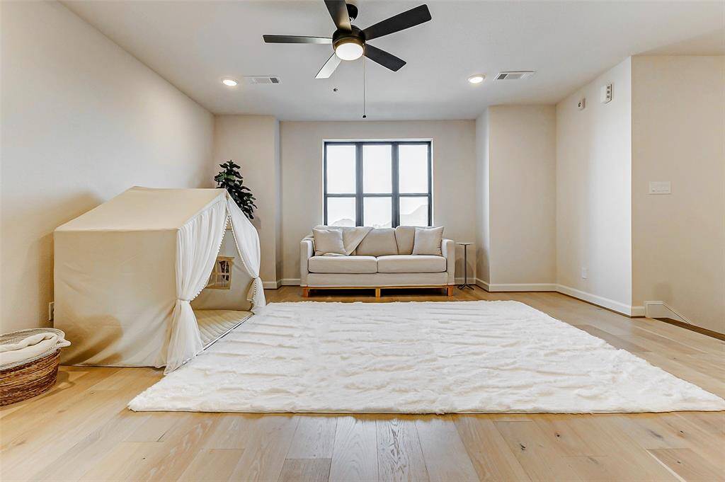 At the top of the stairs, you’re welcomed into a spacious game room featuring wide-plank hardwood flooring, large picture windows, recessed lighting, and a ceiling fan for added comfort. This versatile space is perfect for relaxation, entertaining, or creating a fun retreat for family and friends.