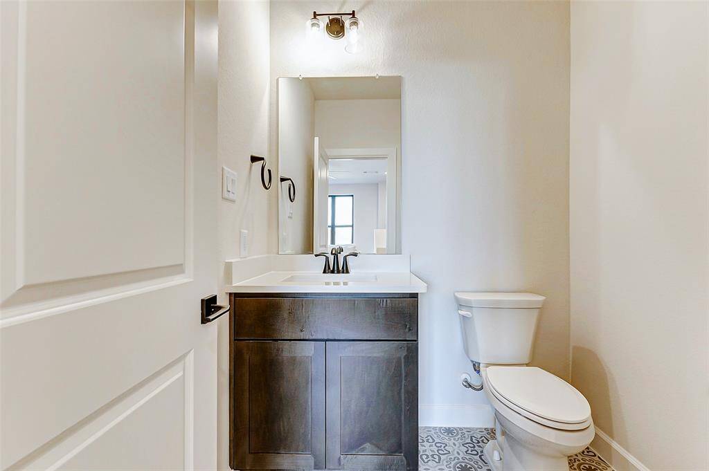 The upstairs half bathroom features a stained wood vanity with ample storage and accent tile flooring. Conveniently located near both the media room and game room, it offers added functionality for guests and family alike.