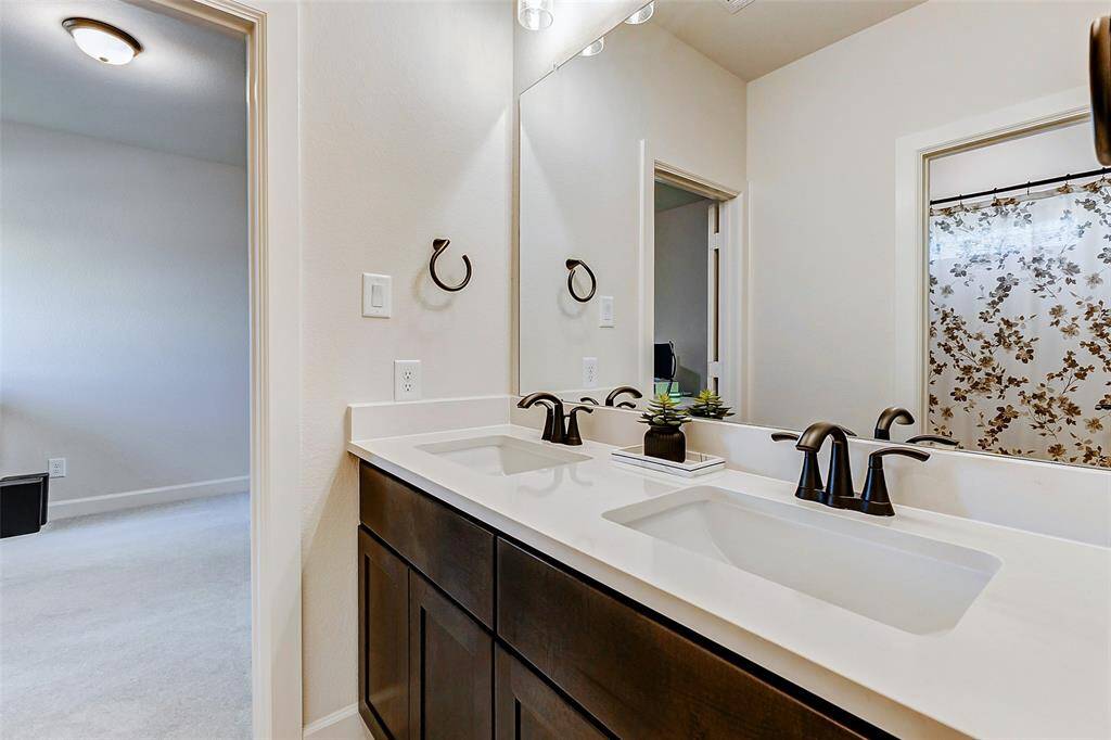 The upstairs bedrooms share a Hollywood bath, featuring a vanity with dual sinks and elegant bronze finishes, combining style and practicality.