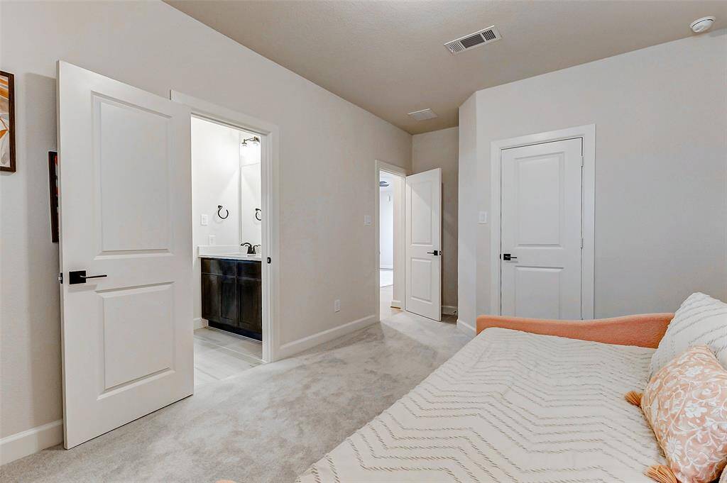 Guest bedroom number two upstairs features plush carpeting, neutral paint, and a spacious closet, offering both comfort and ample storage.