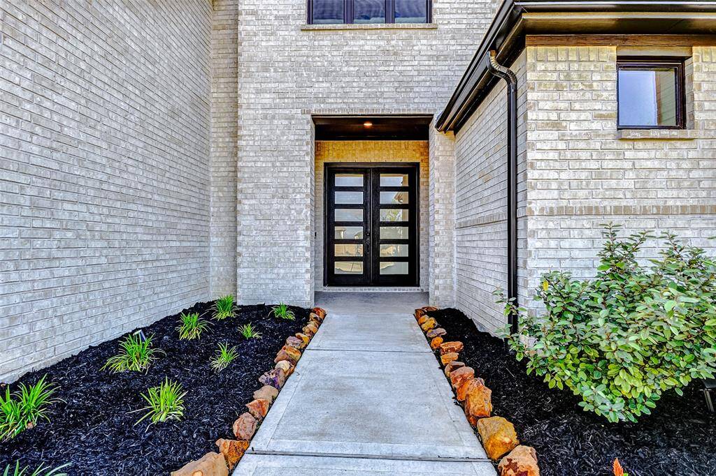 Follow the beautifully landscaped pathway, accented with a stone border, to the inviting front porch framed in timeless brick. Grand leaded-glass double doors make a striking first impression, setting the tone for the elegance and charm that await inside.