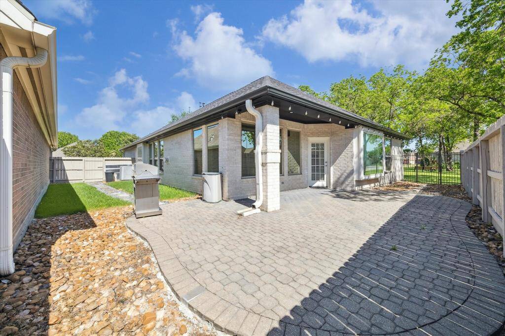 This inviting backyard features a generous, paved patio that's perfect for outdoor entertaining. A covered area offers shade and protection from the elements, making it ideal for year-round enjoyment. Lush greenery and a privacy fence surround the space, creating a peaceful, secluded retreat right at home.