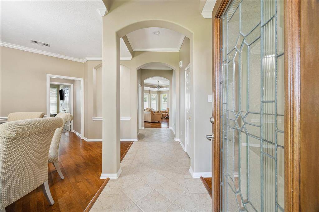 Welcome to a bright, inviting entryway featuring a stylish glass-paneled door, neutral walls, and a mix of tile and wood-like flooring. The open layout leads to a cozy living space with ample natural light, perfect for a comfortable and welcoming home.