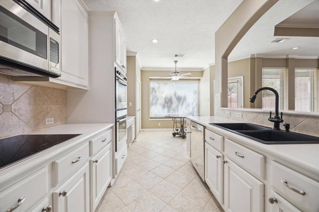 Bright and spacious kitchen with modern appliances, ample cabinetry, and a large breakfast area. It features an elegant archway, tile flooring, and a convenient open layout.