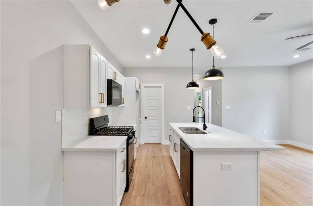Look at this super clean and bright kitchen that features sleek quartz countertops with modern fixtures